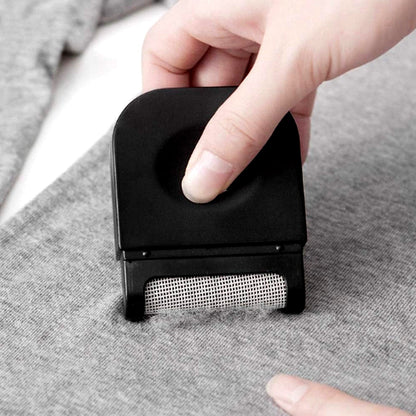 Lint remover demonstrating its detachable fuzz collection compartment.