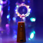 A multi-color LED bottle cork light illuminating an empty wine bottle, creating a festive glow.