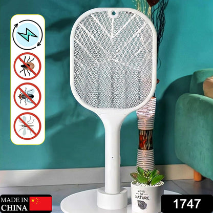 A white mosquito killer racket with a stand is positioned in a room with a teal wall and a green armchair.