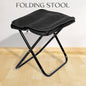 Folding Camping Stool set up in a lush green outdoor setting, ready for use.