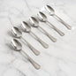 Set of 6 stainless steel dining spoons with polished finish on dining table