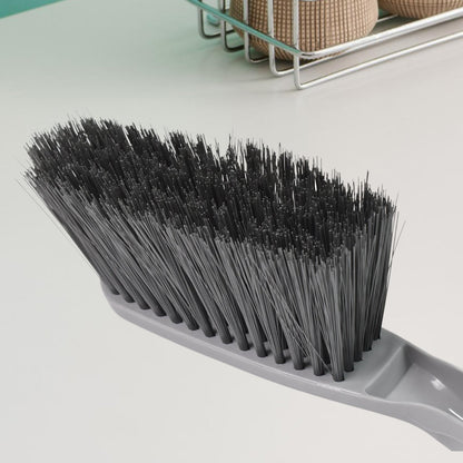 Woman using the long-handle cleaning brush for scrubbing a kitchen sink.