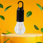 A black and clear portable LED tent light with an orange filament stands on a light wooden pedestal against a bright yellow