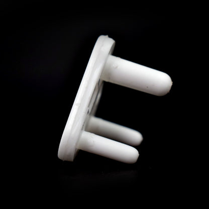 Close-up of a white baby safety socket cover protecting an outlet.