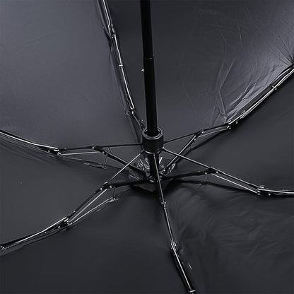 The underside of the black umbrella reveals its metal frame and ribs, supporting the dark fabric canopy.