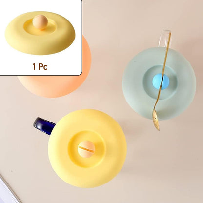 A Tidy Table Silicone Cup Lid in grey, providing an airtight, dust-proof seal on a ceramic mug.