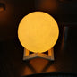 A beautifully lit 3D moon lamp with touch controls on an elegant crystal ball stand.