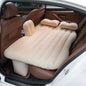 Inflatable car bed with two pillows and pump set up in a car's back seat.
