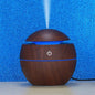 Compact USB desktop humidifier with multi-color LED lights on a clean surface.