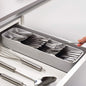 An empty, grey plastic cutlery tray with multiple compartments for kitchen drawer organisation.