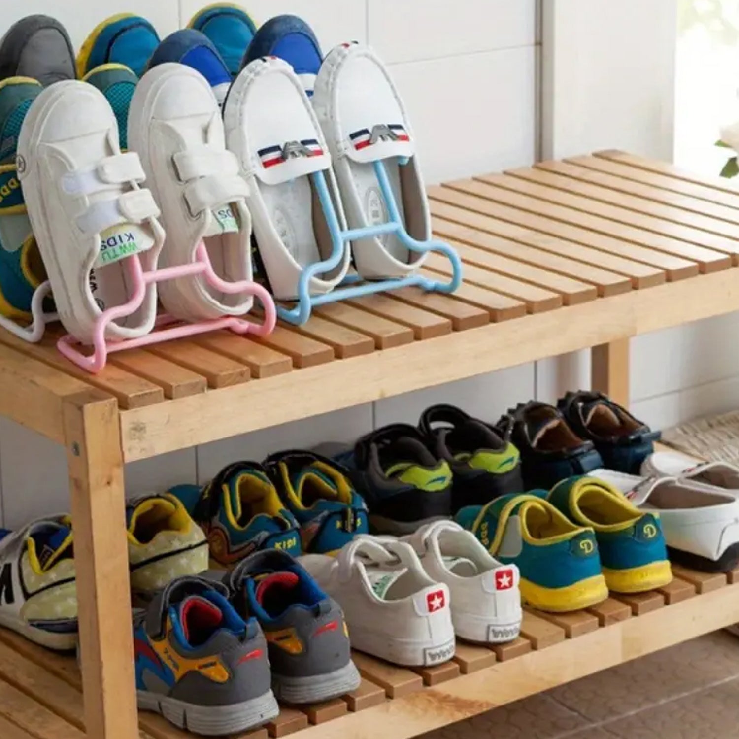 Several pairs of shoes, including white loafers and colorful sneakers, are displayed on a wooden shoe rack, some using the