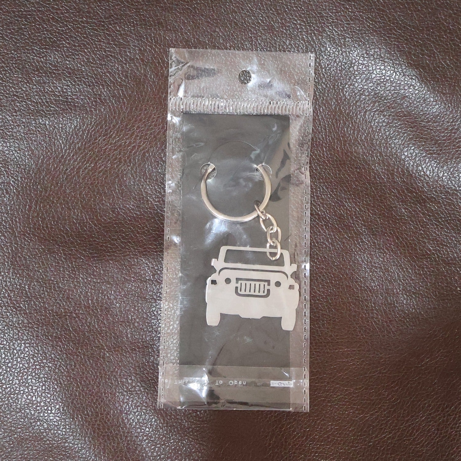 Jeep shaped metal keychain holding keys, displayed in hand