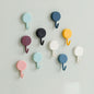 Pack of 10 transparent self-adhesive wall hooks on a white surface.