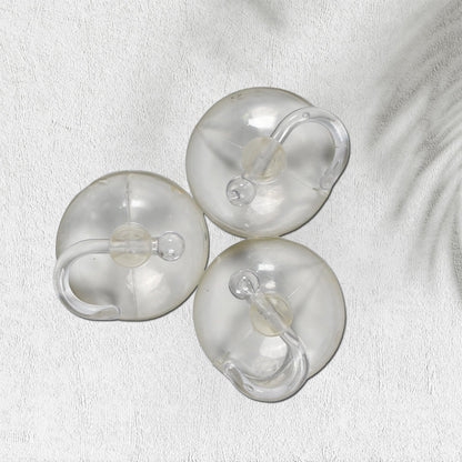 Two transparent suction hooks with strong hold on a bathroom tile wall.