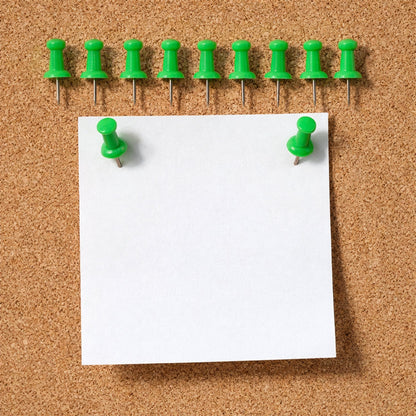 Green push pin fixing paper on a cork notice board