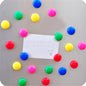 Colorful magnetic pins holding papers on a whiteboard in an office setting.