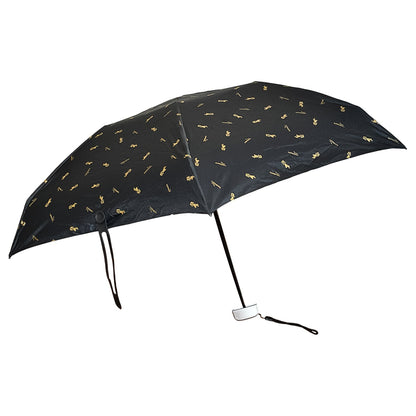 The black compact umbrella is fully open, displaying its gold musical note pattern against a white background.