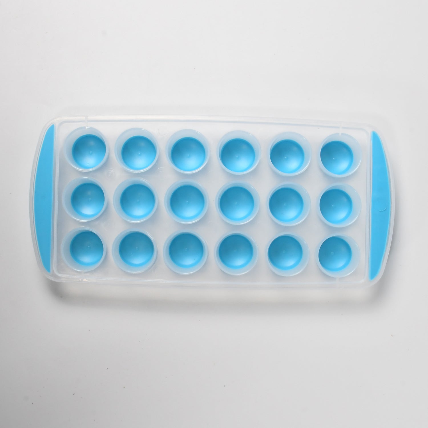Silicone ice cube mold filled with water, ready to be placed in the freezer to make round ice.