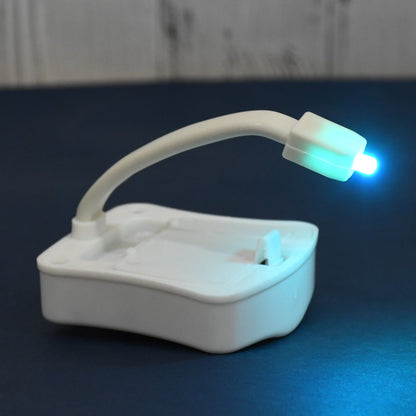The compact LED toilet night light device with its flexible arm for universal fit.