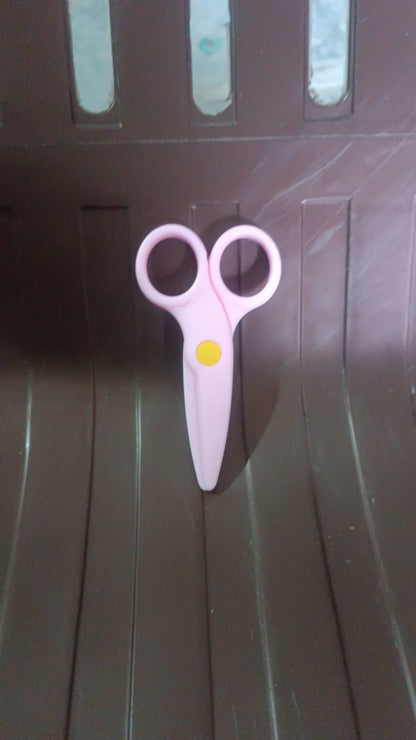 A child happily using the child-safe plastic scissors for an art project.