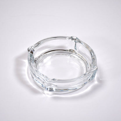 Clear glass ashtray featuring a classic round shape and convenient cigarette slots.