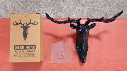 Three deer head wall hooks in black, white, and grey mounted on a wall.