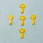 A set of five white self adhesive hooks displayed on a clean surface.