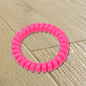 A bulk pack of 100 multi-colored telephone wire hair bands.