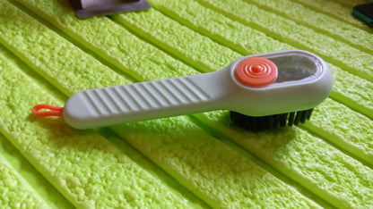 Angled view of the scrubbing brush with dispenser, highlighting its design.