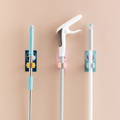 Multiple self-adhesive mop and broom holders neatly arranged on a wall.