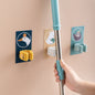 A white self-adhesive mop holder securely gripping a broom handle on a tiled wall.
