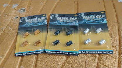 A silver aluminium valve stem cap resting gently on a smooth surface.