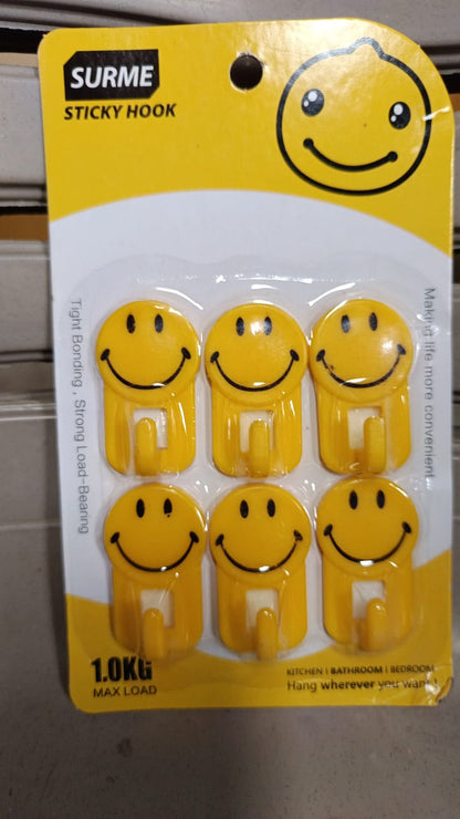 A yellow smiley face adhesive hook against a white background, ready for use.
