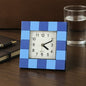 Modern square table clock with a bold frame, displayed on a desk.