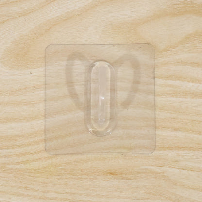 Close-up of transparent wall hook showing its adhesive pad