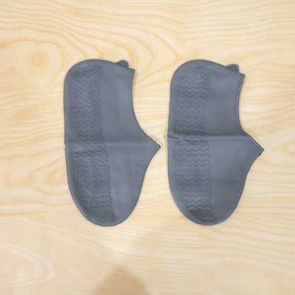 Two gray silicone foot protectors with textured soles are neatly arranged on a light wooden surface.