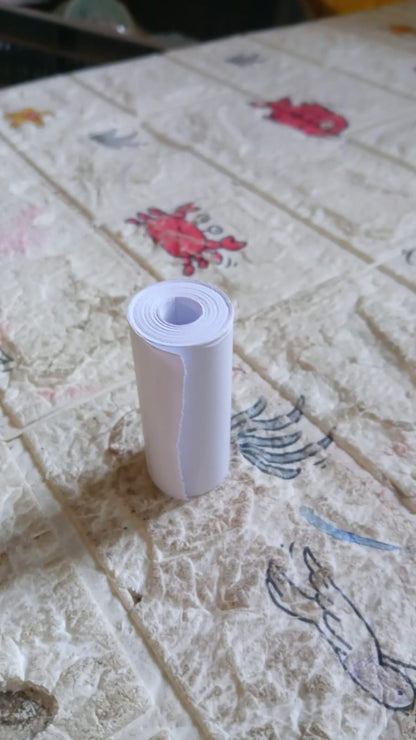 An overhead view of the thermal printer paper roll and a mini printer on a workspace.