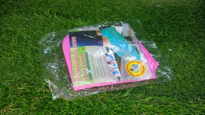 A clear plastic package containing pink and blue silicone shoe covers with product information, resting on green grass.