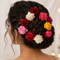 A collection of colourful flower hair pins in mixed hues, laid out for display.
