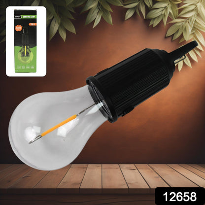 A black and clear portable LED tent light with an orange filament lies diagonally on a wooden surface, with its green and